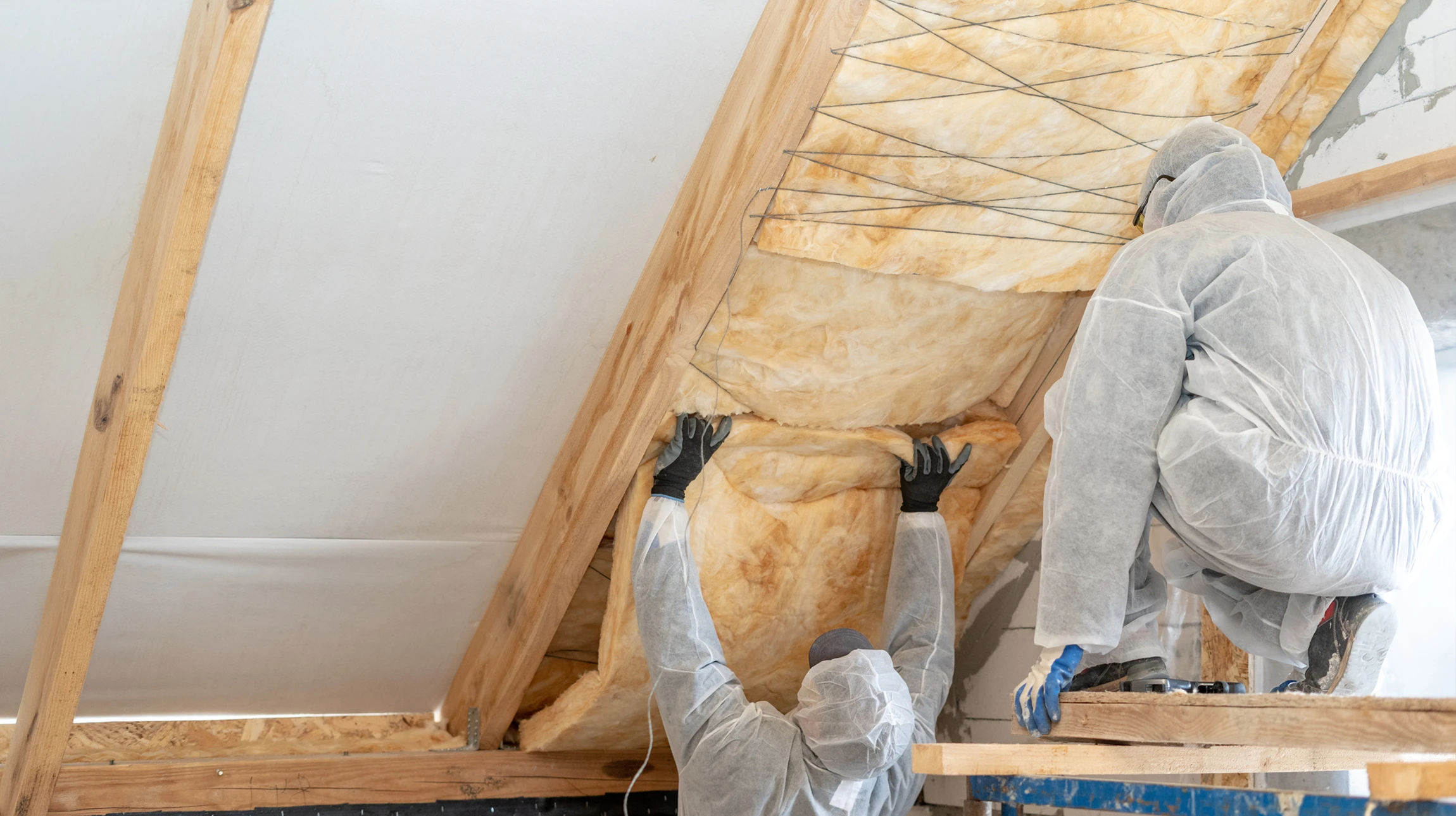 Ouvrier de construction caucasien avec rouleau de matière isolante, plancher isolant par laine minérale