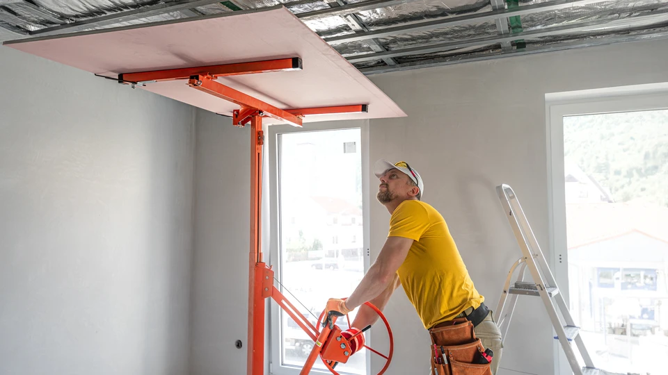 Deux ouvriers installent un plafond suspendu dans un bâtiment en construction